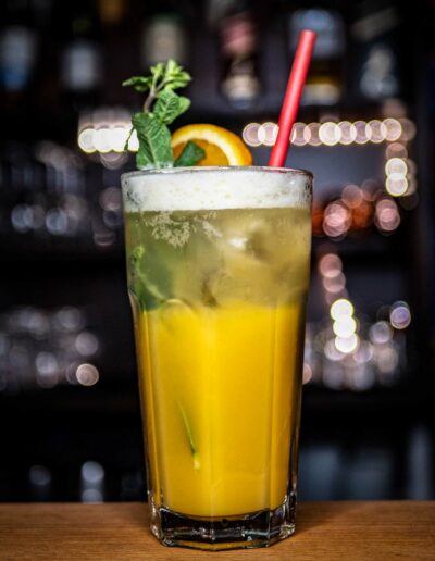 Orangefarbener Cocktail mit Orangenscheibe und Strohhalm